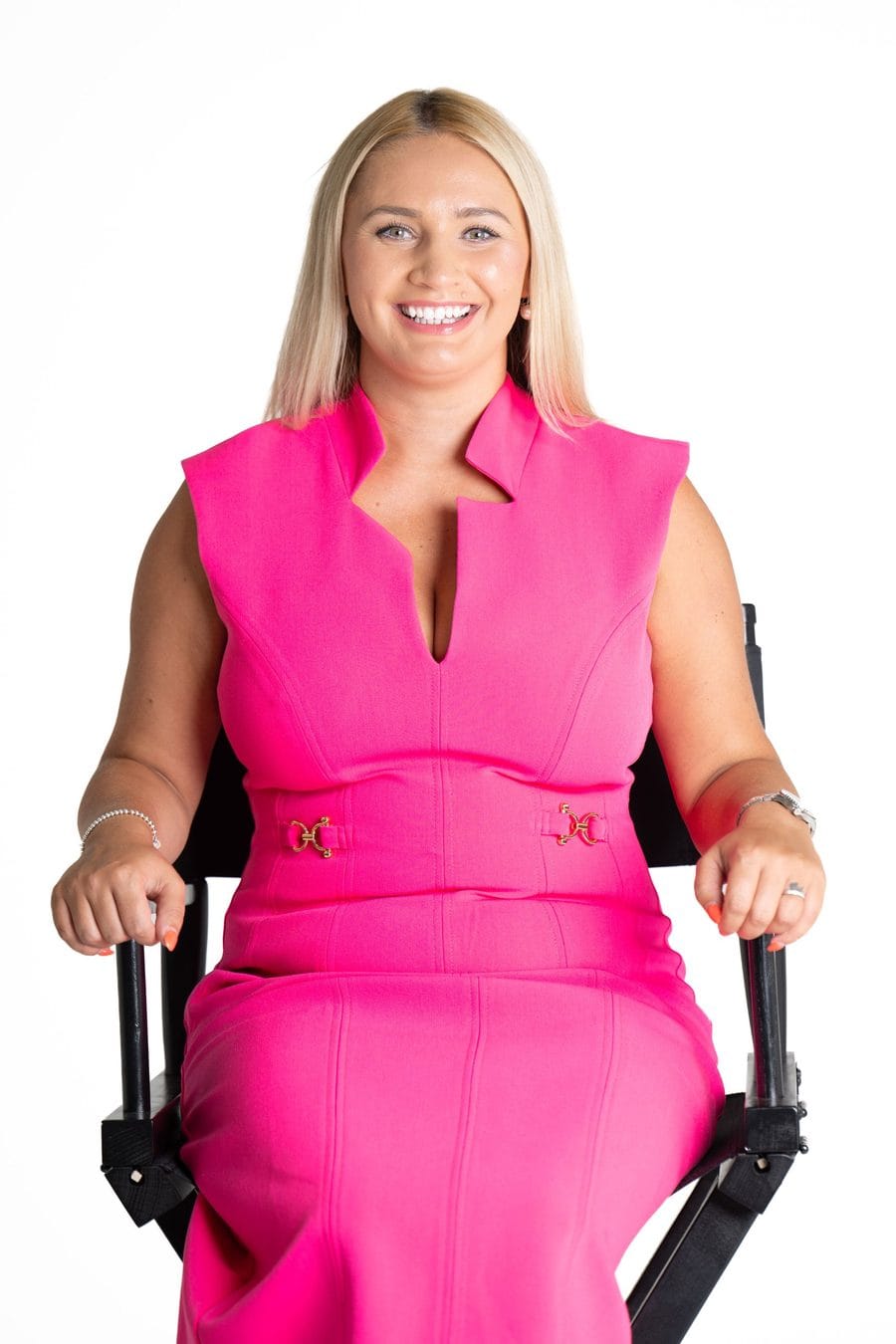 Emily Mallender in a pink dress on the director's chair at EMpowered Media Studios